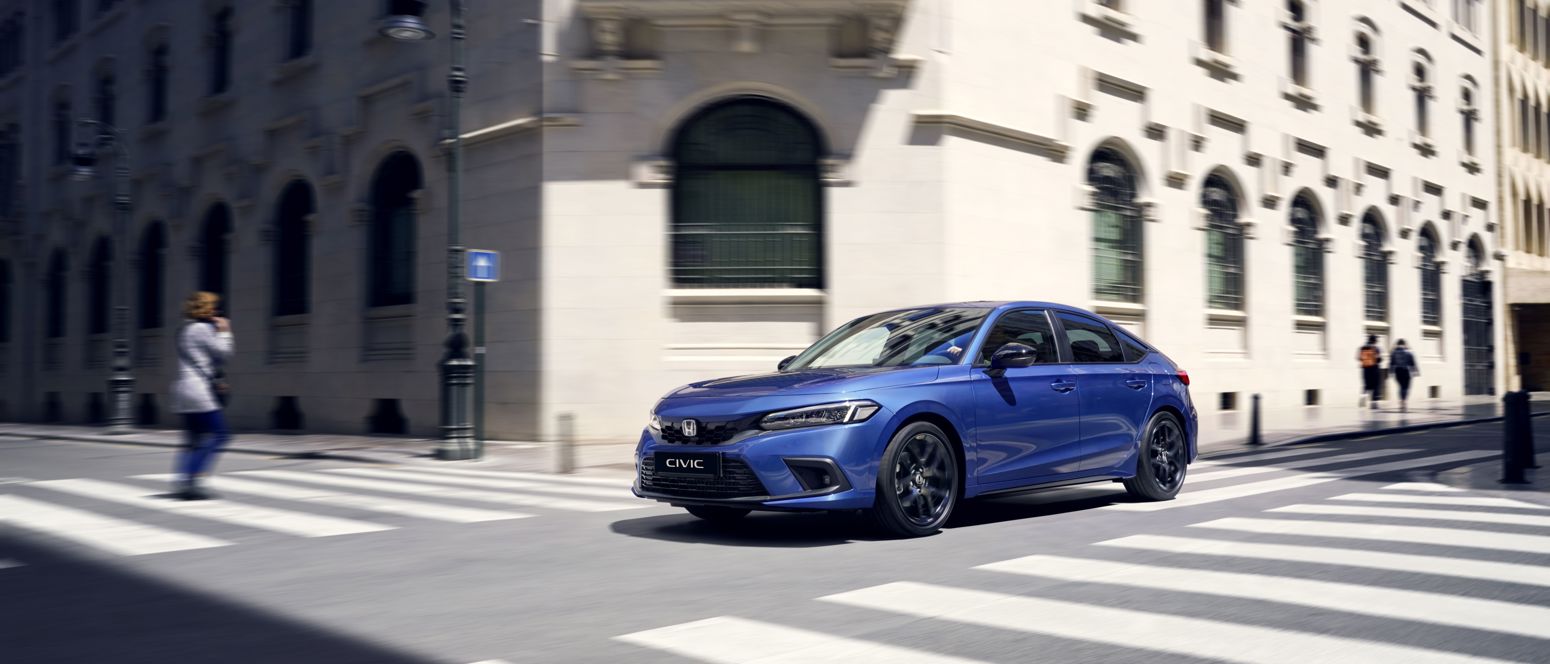 Honda Civic in blue colour driving through the city.