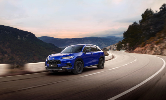 Honda ZR-V in Still Night Blue Pearl Driving on a curvy hillside road.